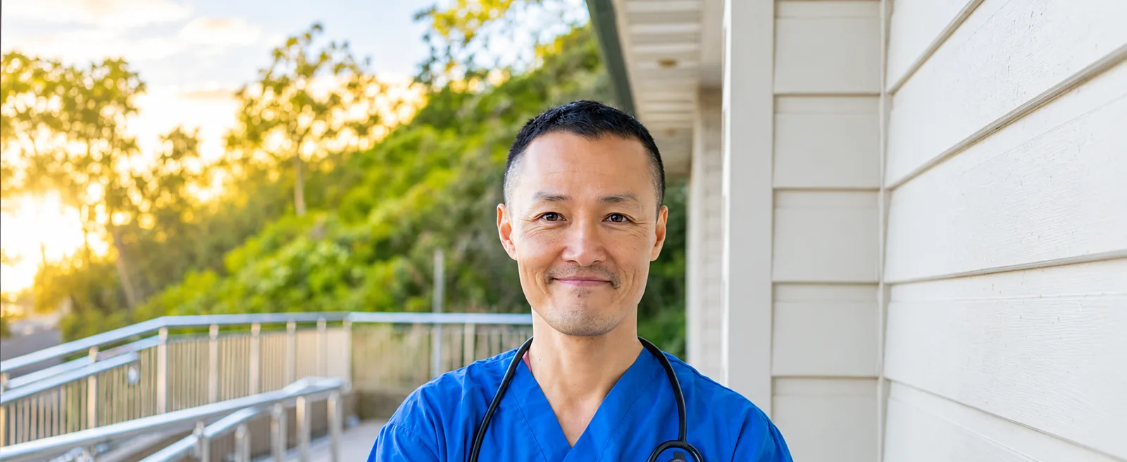 Doctor in blue scrubs with a stethoscope on a sunny veranda