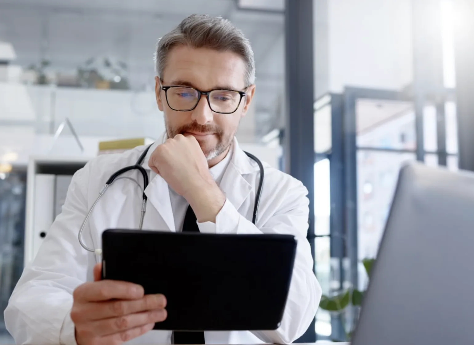 Doctor in a white coat reviewing notes on a tablet