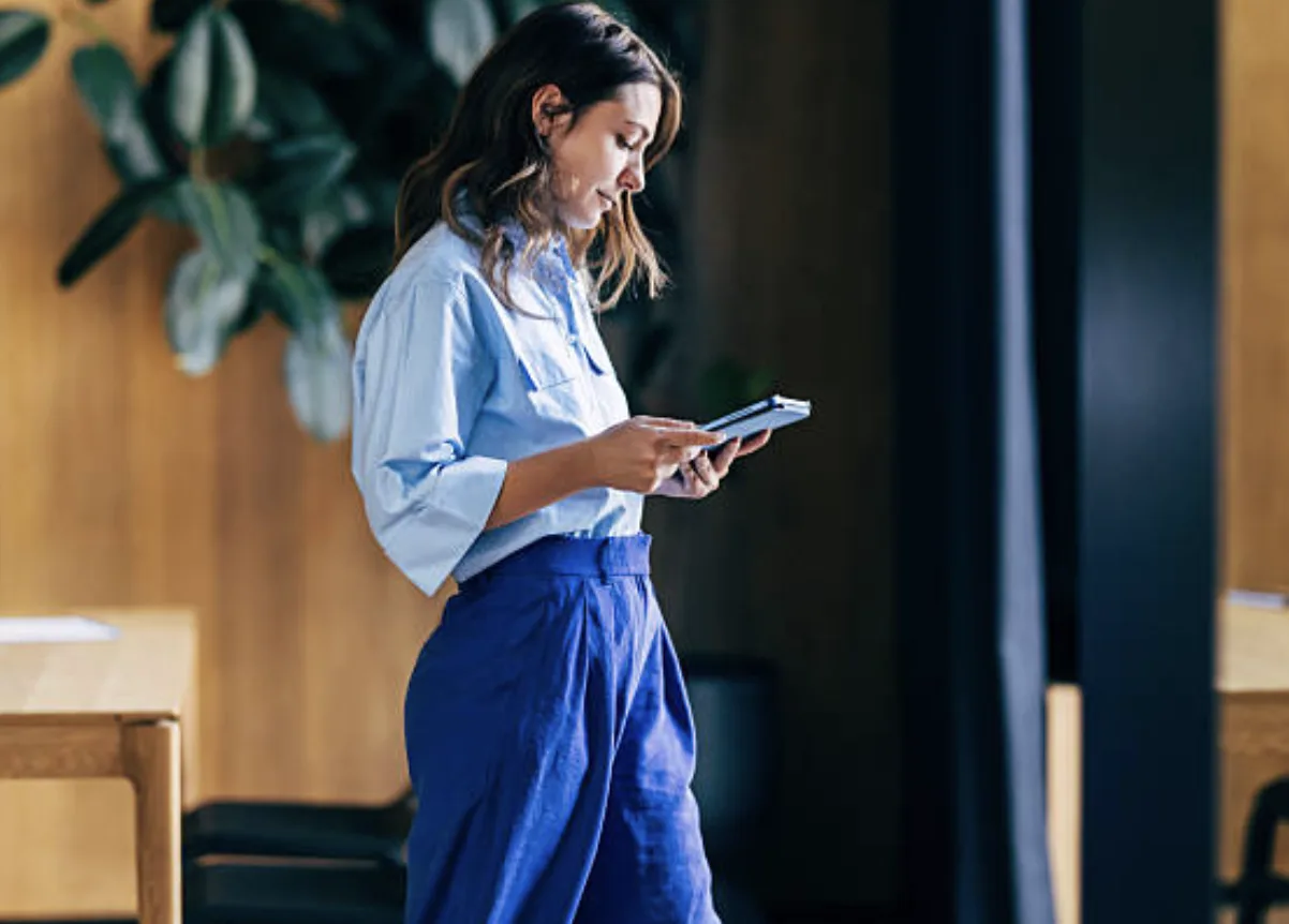 Woman in a blue shirt reading her phone in an office
